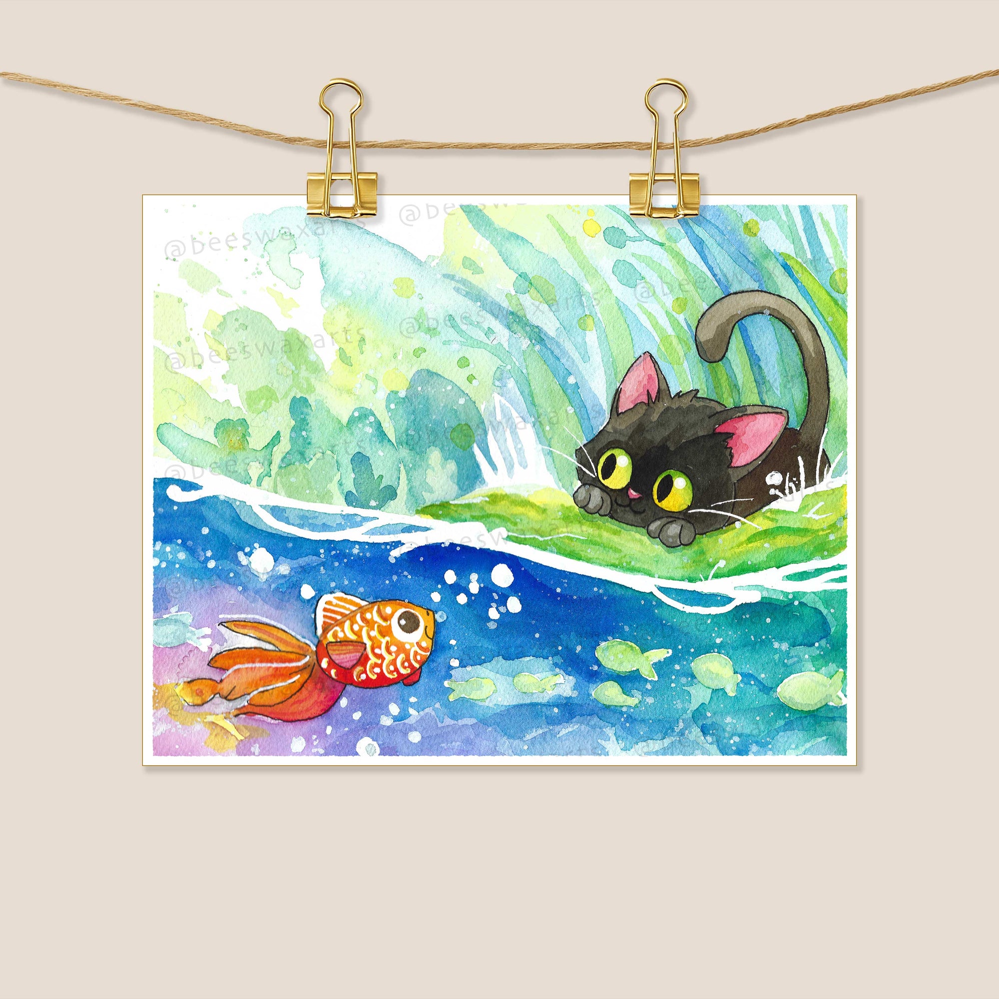 Unexpected Friendship Cat and Goldfish by Beeswax Arts Watercolors shows a black cat with green eyes watching an orange goldfish among lily pads. Clipped to a string with gold binder clips, this print is a unique gift for art lovers.