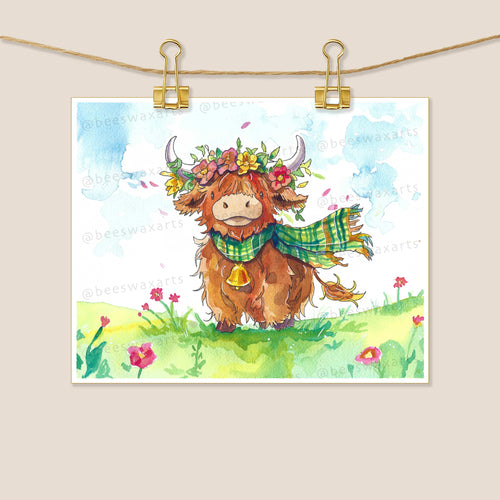 The Highland Cow by Beeswax Arts Watercolors features a smiling brown cow and fluffy alpaca in green plaid scarves and flower crowns, standing on grassy pink flowers under a blue sky, clipped to a string with gold clips.