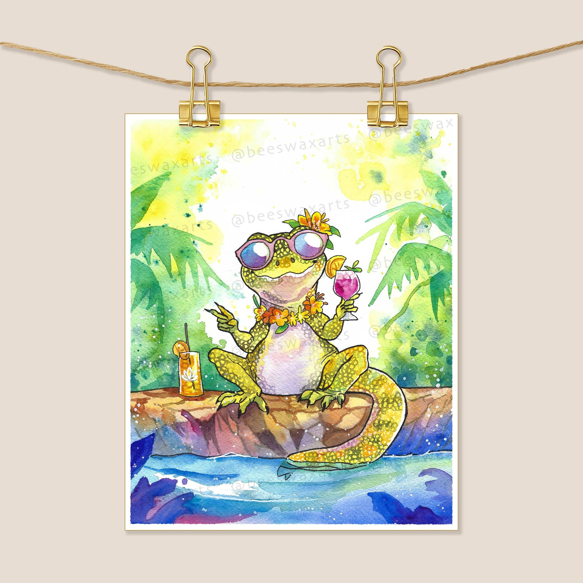 Monitor Lizard at the White Lotus by Beeswax Arts Watercolors features a laid-back lizard in sunglasses, flower crown, and lei, relaxing by water with a drink—ideal as an archival art print for collectors.