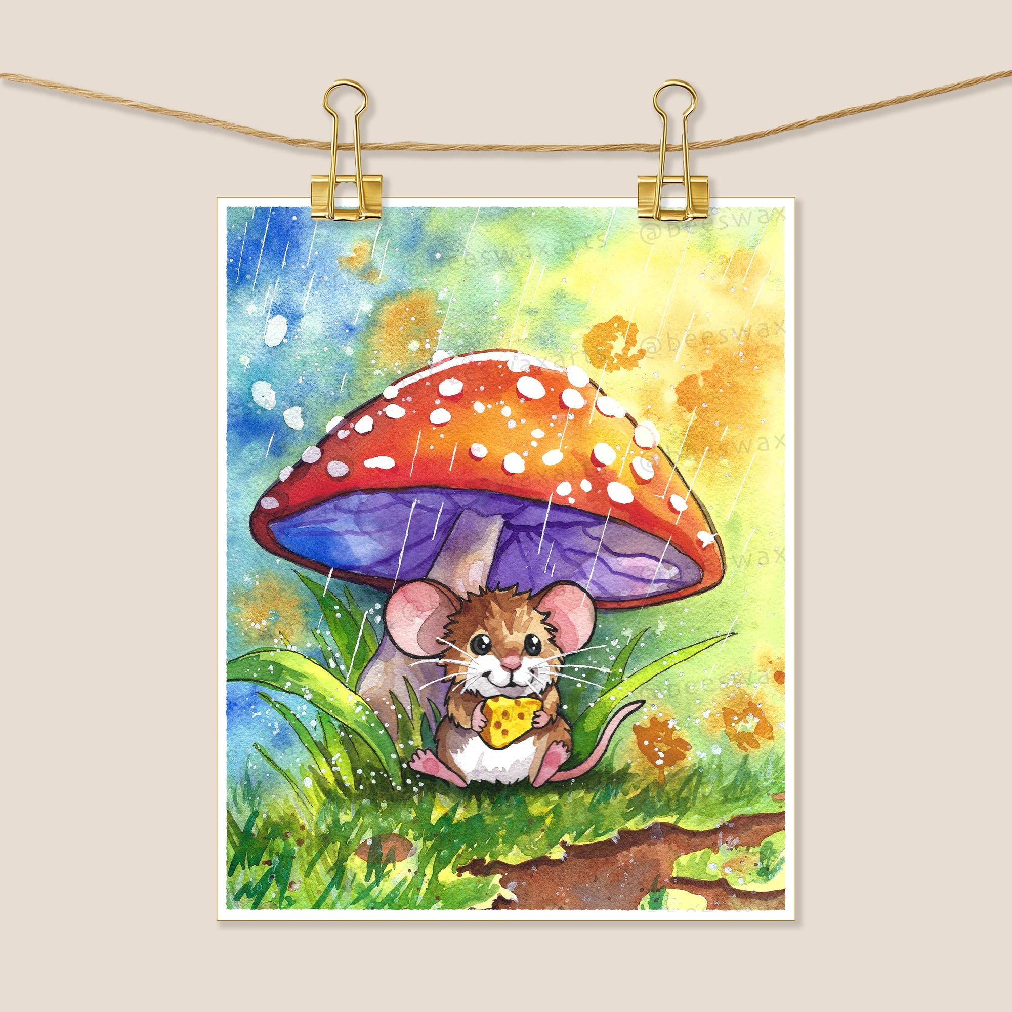 “Mouse Snacktime” by Beeswax Arts Watercolors features a mouse with cheese sheltering under a red-and-white mushroom in the rain. This collectible art uses vibrant colors and is printed on archival paper.