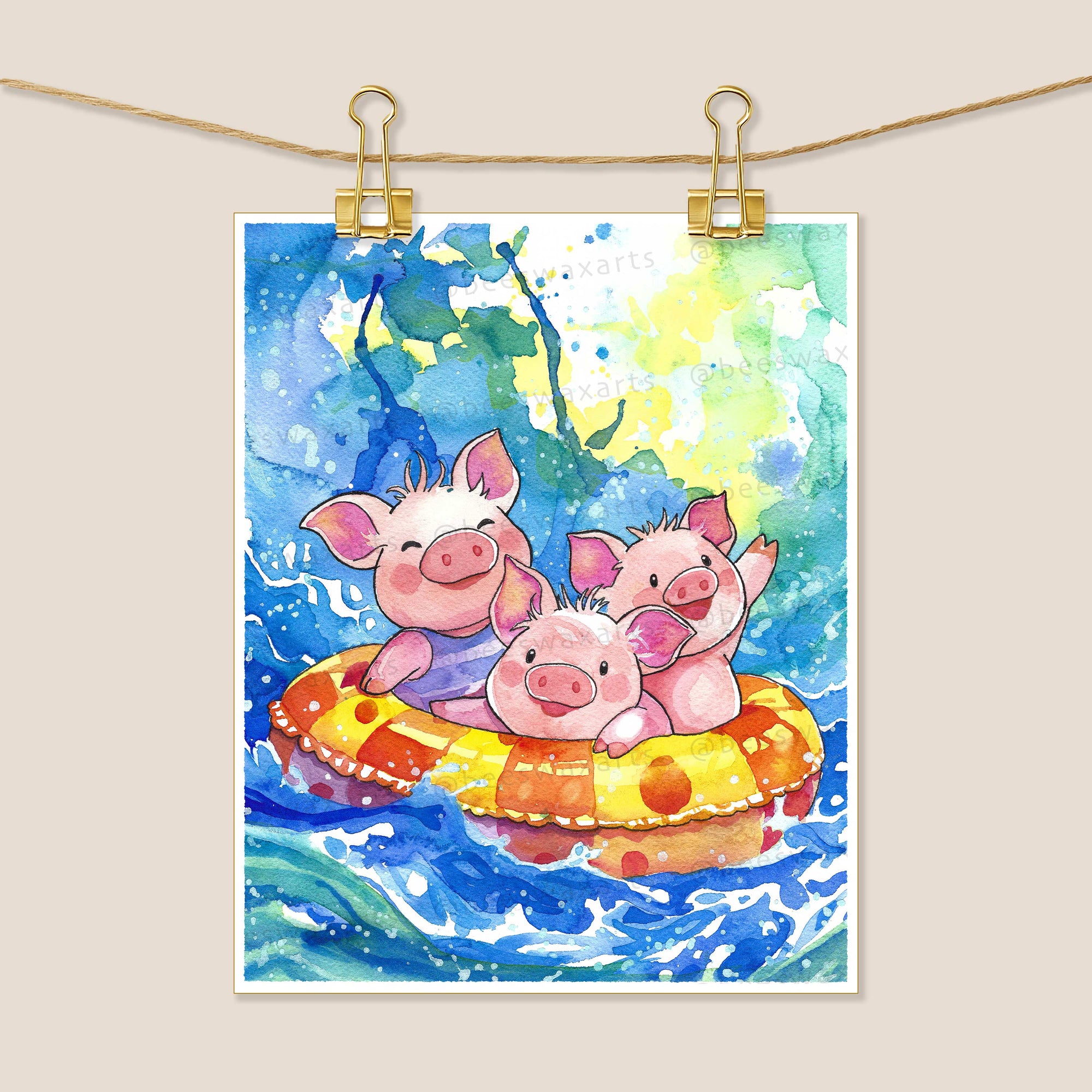 The Pig Island 8x10 art print by Beeswax Arts Watercolors features three smiling piglets in a yellow-orange raft on blue water, clipped to a string with gold clips.